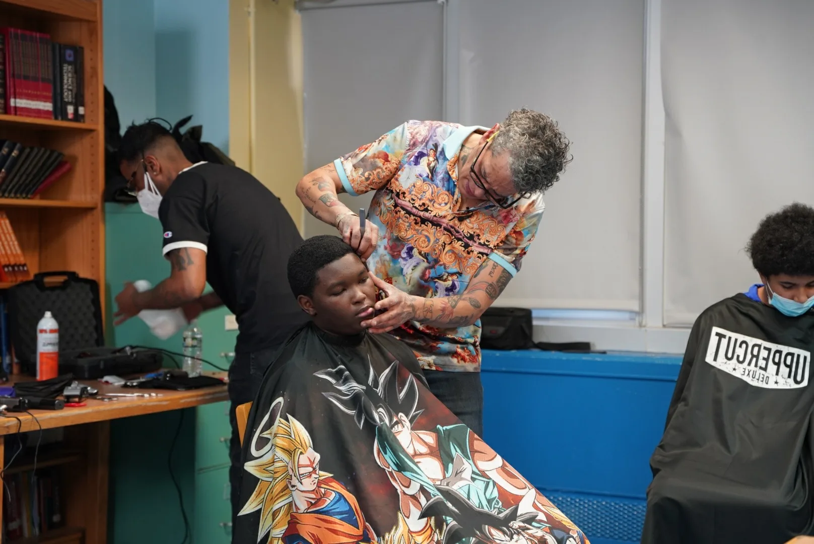 Barber cutting a student's hair at a grooming station in a school room.