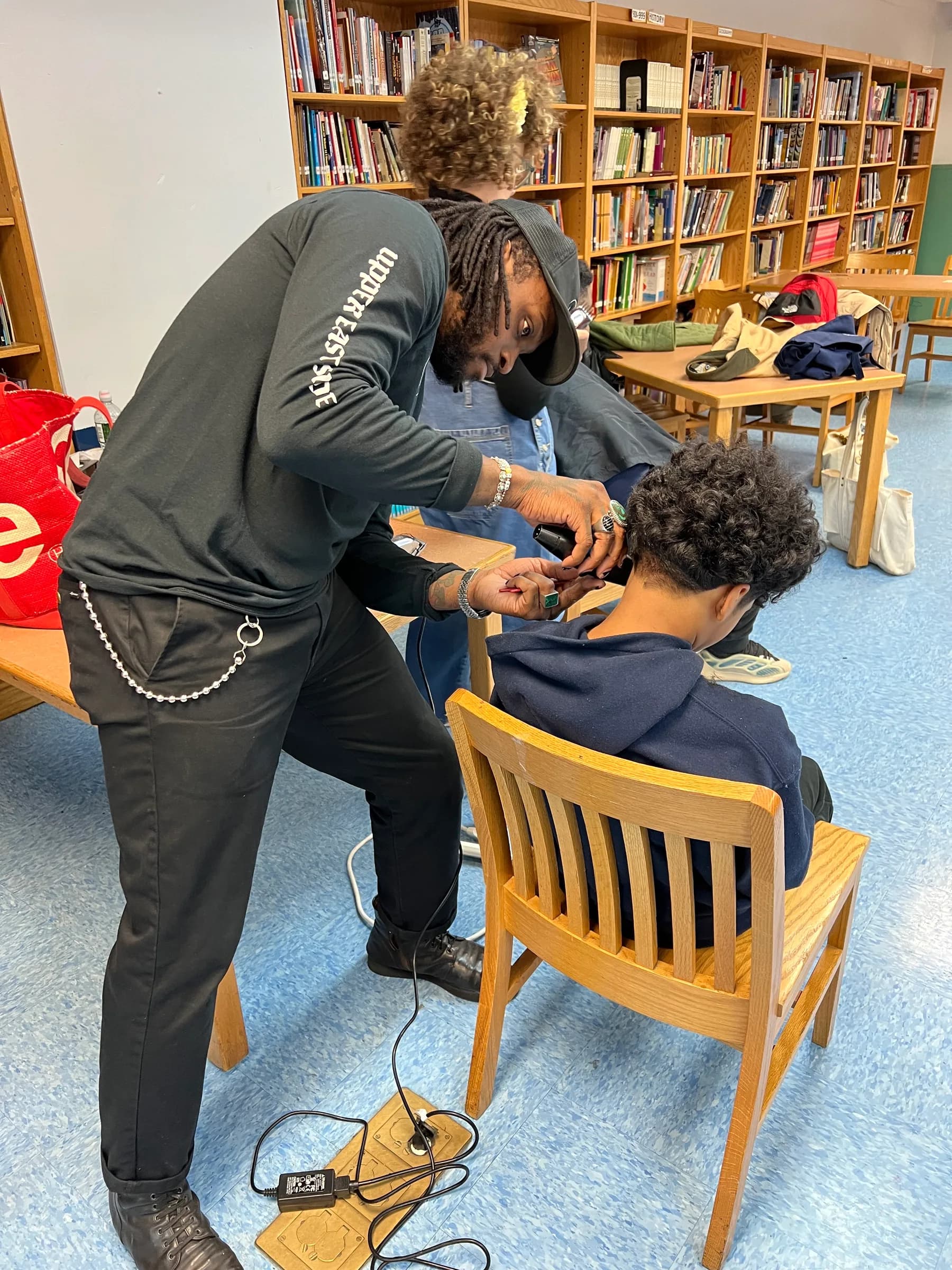 Barber working closely on a student's haircut during a school session.