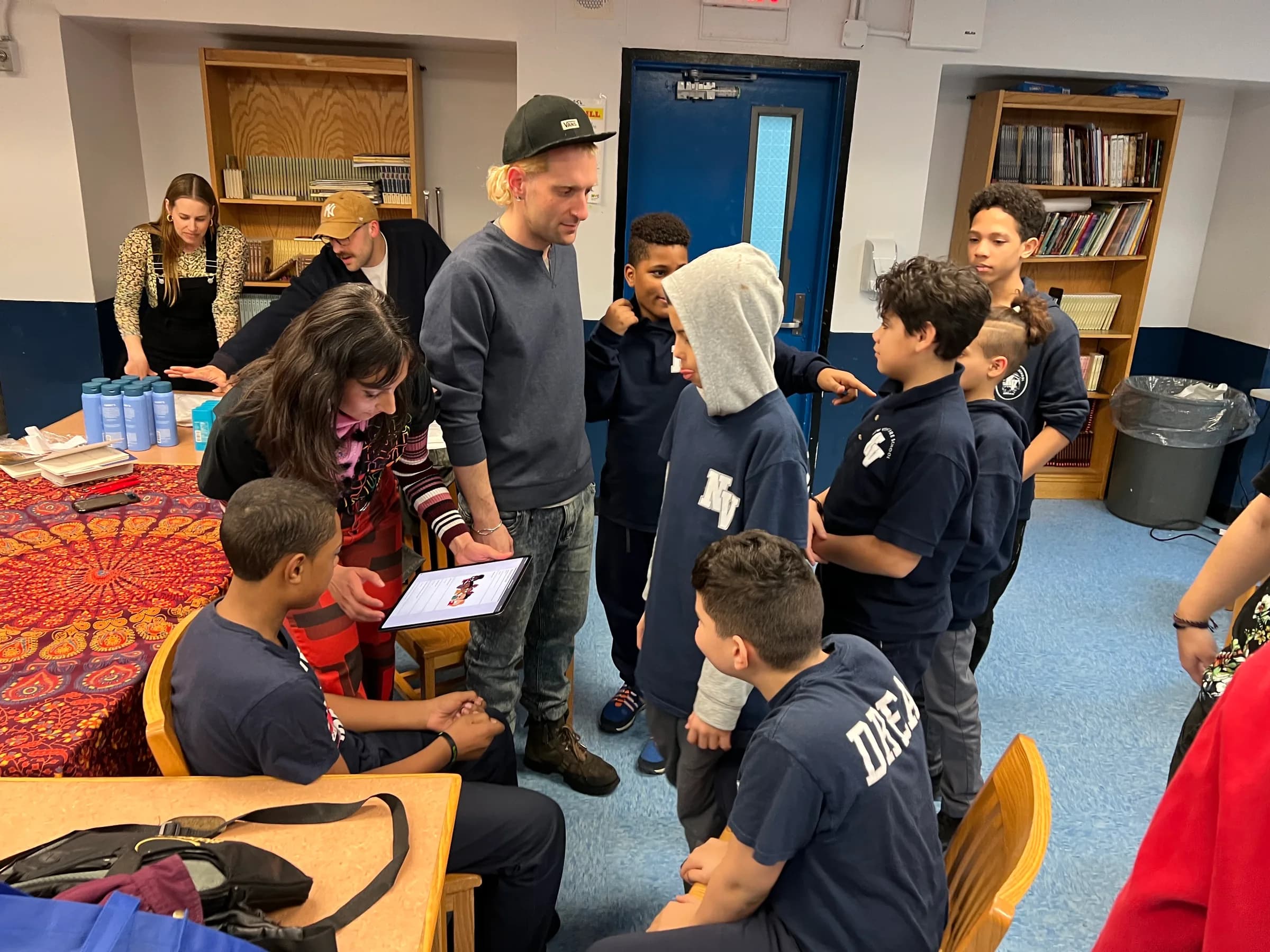 Students gathered around a table and screen during a grooming-product activity.