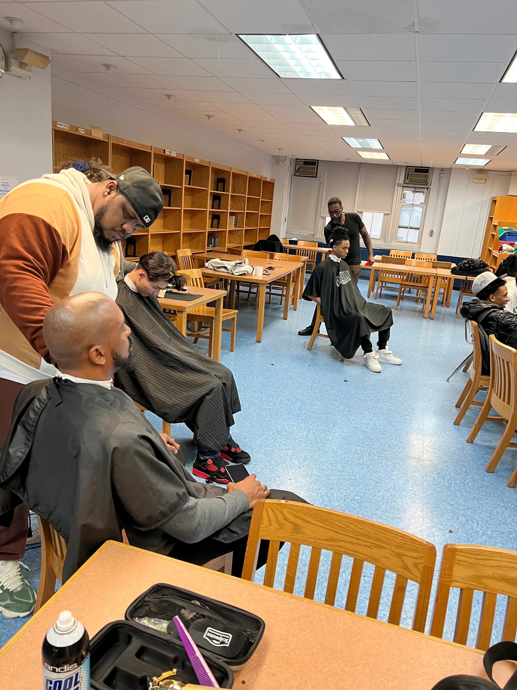 Several barbers working at grooming stations in the same school room.