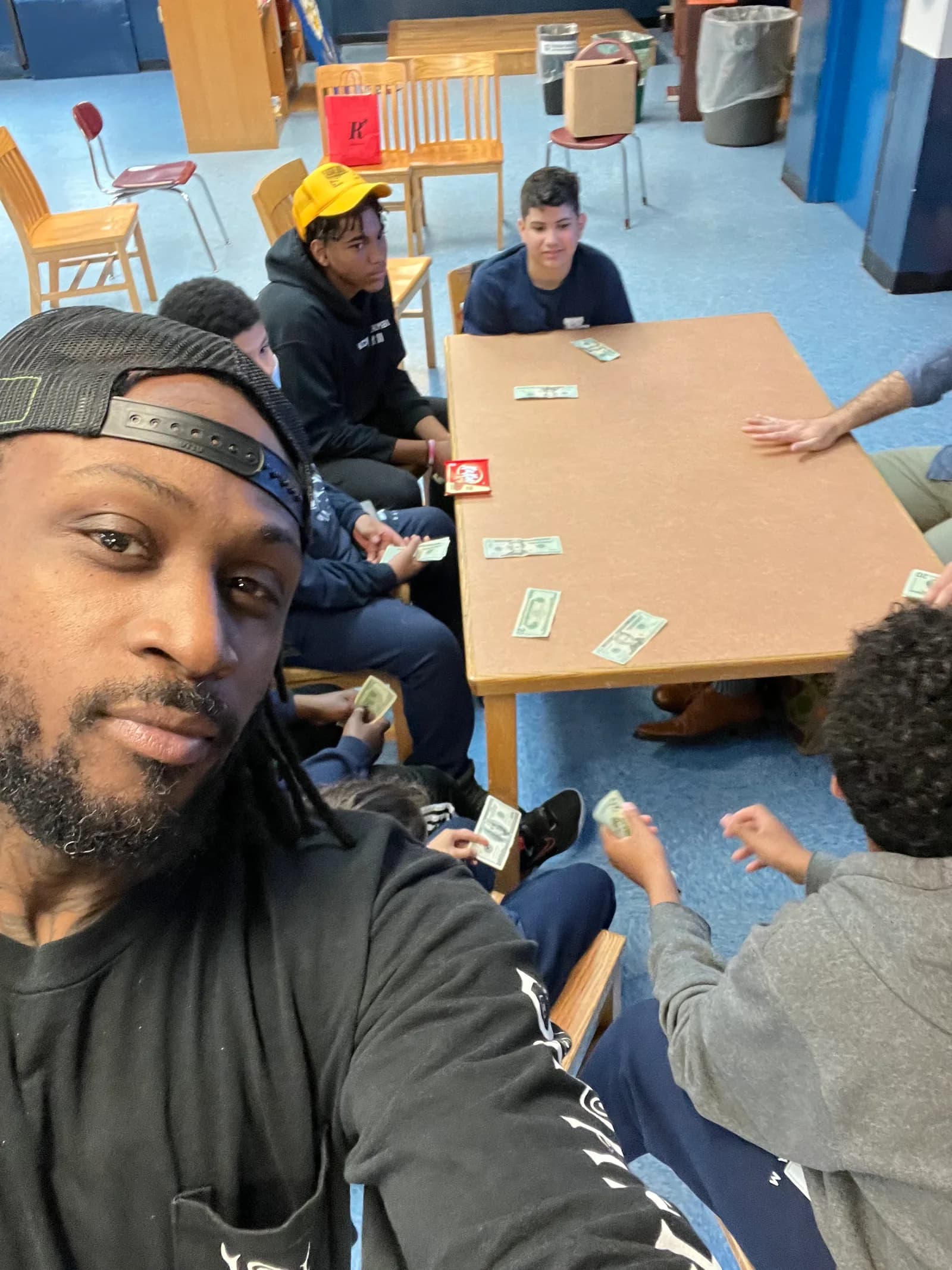 Participants gathered around a table holding play currency during a finance exercise.