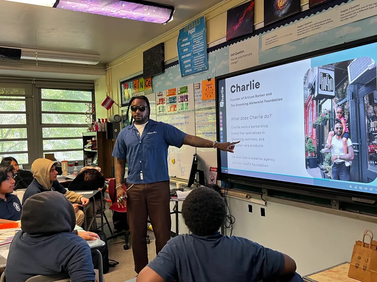 Career Day speaker presenting to students beside a classroom screen.